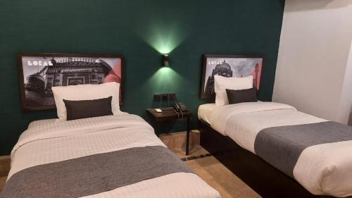 2 łóżka w pokoju z zielonymi ścianami w obiekcie LOKAL Rooms x Multan (City Center) w mieście Multan