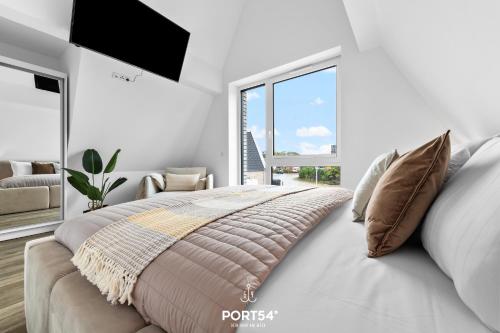 ein weißes Schlafzimmer mit einem großen Bett und einem Fenster in der Unterkunft Ferienwohnung Inselfeeling Fehmarn in Fehmarn