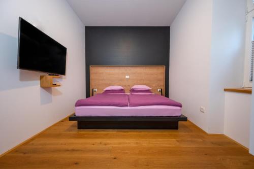 a bedroom with a purple bed and a flat screen tv at Cirus apartments in Kočevje