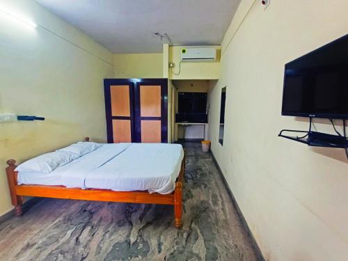 a small room with a bed and a flat screen tv at STAYMAKER Unnatha Residency in Manipal