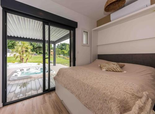 een slaapkamer met een bed en uitzicht op een zwembad bij VILLA ***** PISCINE CHAUFFÉE, JACCUZI, PÉTANQUE in Moirax