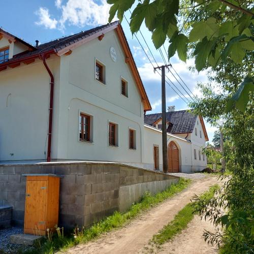 una casa blanca con una pared de ladrillo junto a un camino de tierra en Apartmány Marie Albeř, en Nová Bystřice