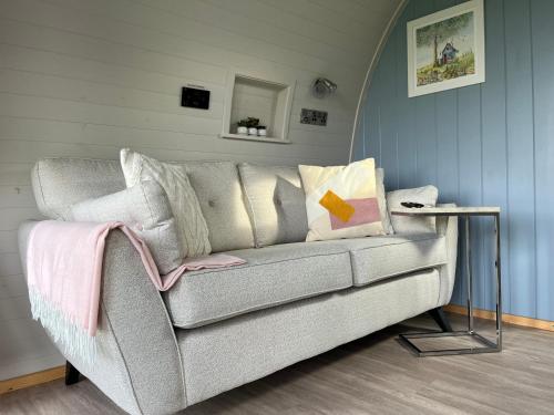 a living room with a gray couch with pillows at Warren Farm Retreat - Pod 1, Pod 2, and The Lodge by SSW in Cardiff