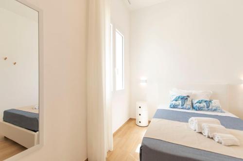 a white bedroom with two beds and a mirror at B&B Villaggio Dei Pescatori in San Vito lo Capo