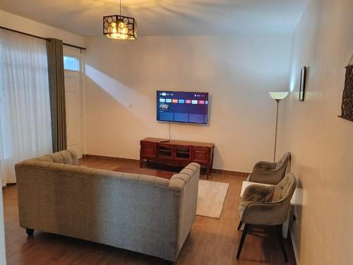 a living room with a couch and a flat screen tv at The Crib House-Kitengela in Kitengela 