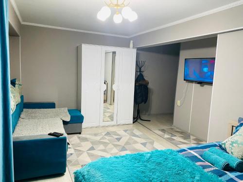 un salon avec un canapé bleu et une télévision dans l'établissement Апартаменты на Бурова, à Öskemen