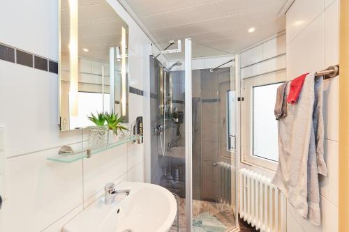 a white bathroom with a sink and a shower at Hotel Berghof in Baumholder