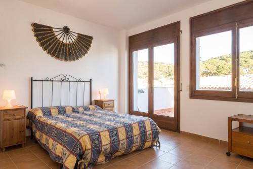 a bedroom with a bed and a large window at Ca l'Estany Clos in Tamariu