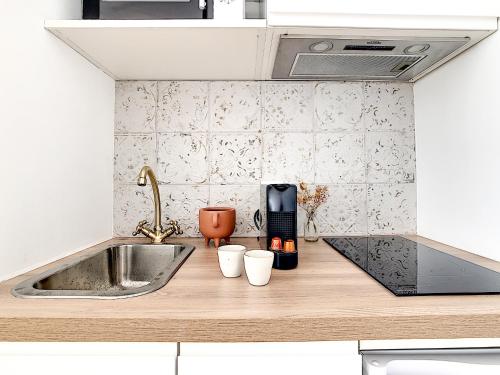 - un comptoir de cuisine avec un évier et 2 tasses dans l'établissement - Maison ÛMA - Wifi, Netflix, Mer et Centre, à Marseille