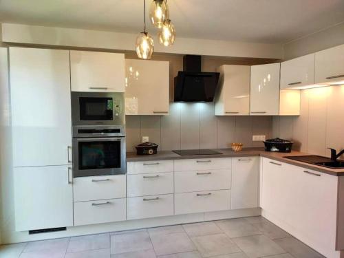 a white kitchen with white cabinets and appliances at Maison individuelle, 10 minutes de Colmar 4 chambres - 8 personnes - 2 sdb in Wintzenheim