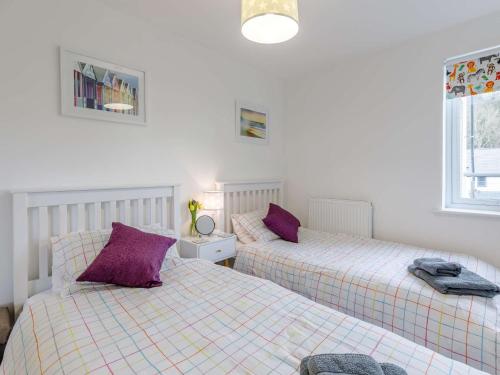 two beds in a room with purple pillows at 2 bed in Caernarfon 86260 in Y Felinheli
