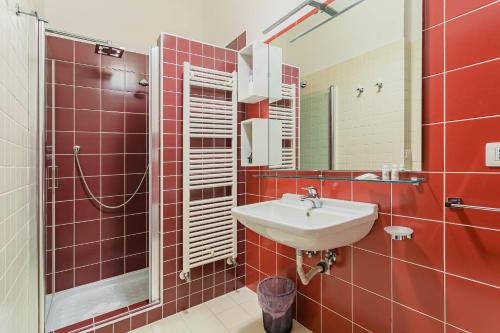 un bagno piastrellato rosso con lavandino e doccia di Helios Rooms by Wonderful Italy a Conversano