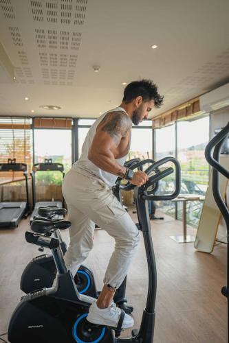 a man riding on an exercise bike in a gym at Best Western Linko Aubagne in Aubagne