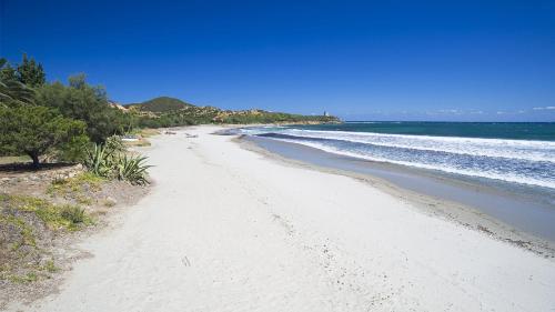 una playa de arena blanca con árboles y el océano en Villetta a 500metri dal mare con bellissima vista, en Tertenìa