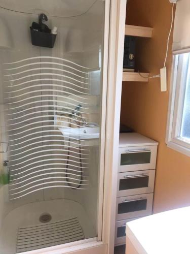 une douche en verre dans une salle de bain avec un lavabo dans l'établissement Les Grands Pins emplacement numéro 103, au Castellet