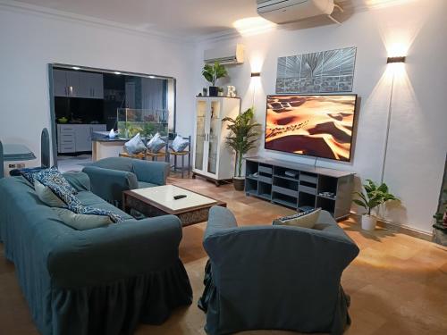 sala de estar con sofás azules y TV de pantalla plana en Vila Maia, en Hurghada