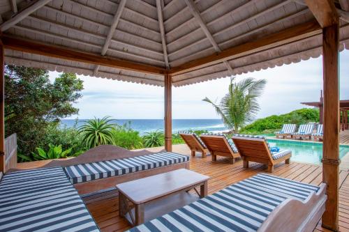 an outdoor patio with chairs and a pool at Aloha 7 in Ponta Mamoli