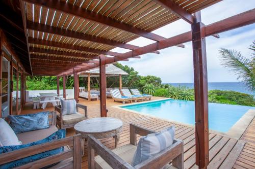 an outdoor patio with a pool and a wooden deck at Aloha 7 in Ponta Mamoli