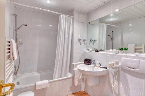 a white bathroom with a sink and a bath tub at Hotel Alt Vellern in Beckum