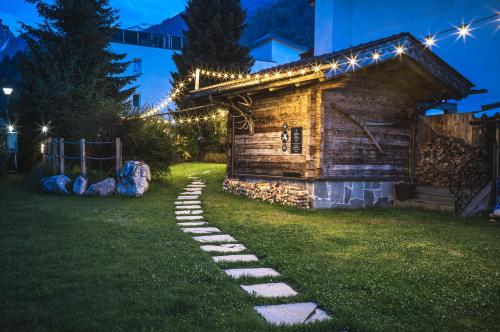 un chemin dans une cour la nuit avec des lumières dans l'établissement Das Falkenstein, à Kaprun