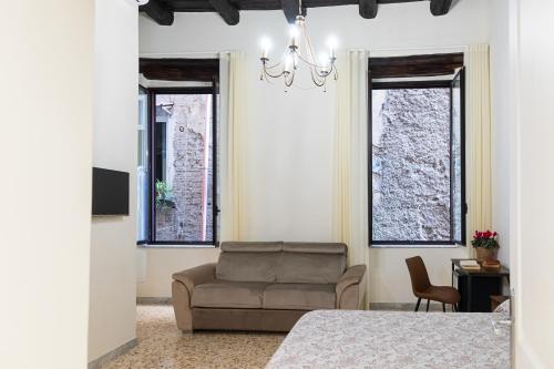 a bedroom with a couch and a chair and windows at LA MASCHERA DI PULCINELLA in Naples
