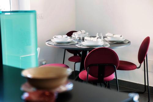 a table with red chairs and white dishes on it at Rosso Sunset - by MyHomeInComo in Colonno