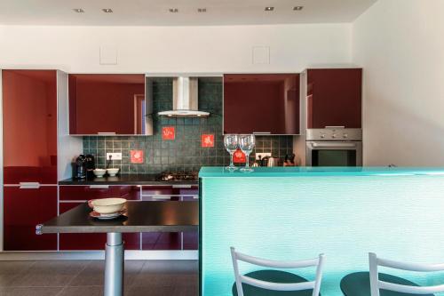 a kitchen with red cabinets and a table and chairs at Rosso Sunset - by MyHomeInComo in Colonno