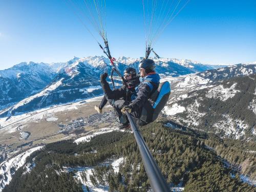 two people riding on a parachute in the mountains at Das Falkenstein in Kaprun