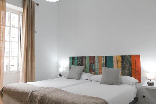 Dormitorio con cama blanca y cabecero colorido en MonKeys Apartments Lumbreras Deluxe, en Sevilla