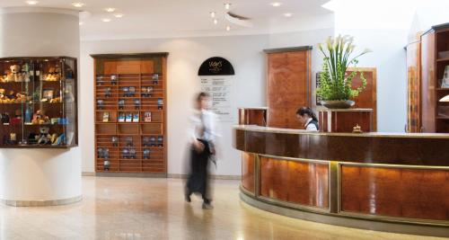 a woman standing at a counter in a store at Victor's Residenz-Hotel Frankenthal in Frankenthal