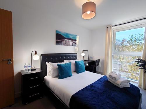 - une chambre avec un lit doté d'oreillers bleus et d'une fenêtre dans l'établissement Three Bed Serviced Apartment by London ExCeL, à Londres