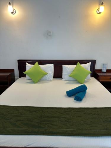 a bed with green and white pillows on it at Natures Bliss Holidays in Ja-Ela
