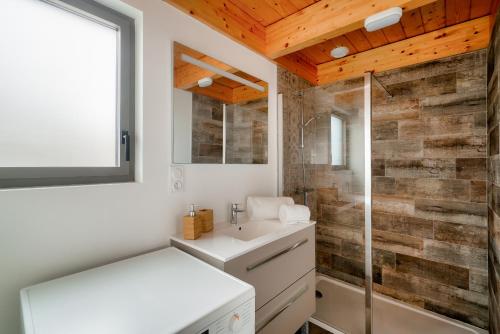 une salle de bain avec un lavabo blanc et une douche dans l'établissement Duplex à 100m de la plage de Pors Carn - Surf, à Penmarcʼh