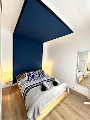 une chambre avec un grand lit avec un mur bleu dans l'établissement L’esplanade du lac, à Gérardmer
