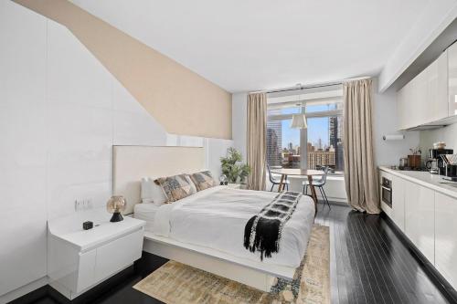 a white bedroom with a bed and a table at Financial District studio w WD gym elevator NYC-1359 in New York