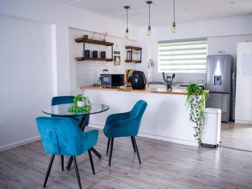 une cuisine avec une table en verre et des chaises bleues dans l'établissement 2 Bedroom Apartment with Modern Finishes Hill Tud Stays, à Pietermaritzburg