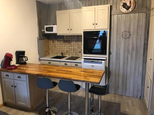 a kitchen with a counter with stools and a microwave at studio tout confort au pied des pistes du lioran in Laveissière