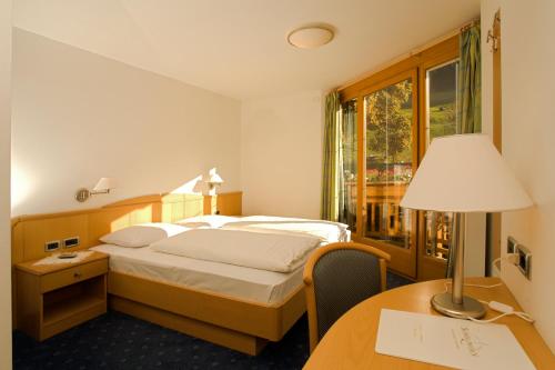 Habitación de hotel con cama y escritorio con lámpara. en Hotel Schölzhorn Superior en Racines