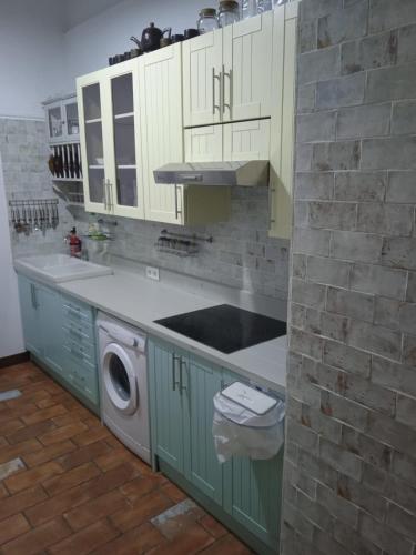 a kitchen with green cabinets and a washing machine at La gota de leche 4 in Sanlúcar de Barrameda