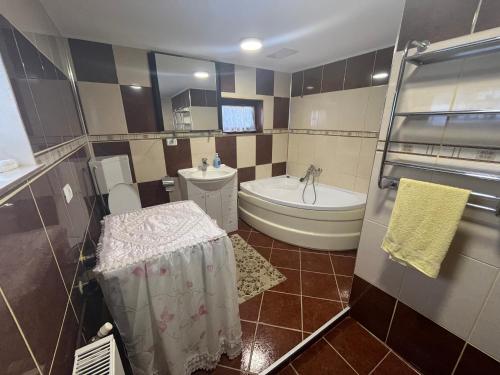 uma casa de banho com uma banheira, um WC e um lavatório. em Pensiunea Valea Dorului em Fundstica