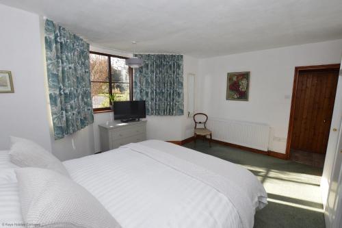 a bedroom with a white bed and a television at The Den in Sheringham