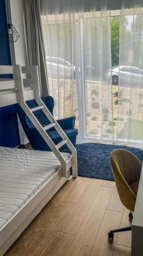 een slaapkamer met een stapelbed, een stoel en een raam bij Biała Perła Czarna Góra Resort Apartament 102 in Siena