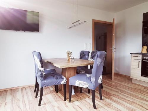 a dining room with a wooden table and blue chairs at Appartements Höpfl in Westendorf