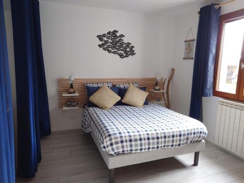 1 dormitorio con 1 cama con cortinas azules y ventana en Cigaléo, Chambre d'hôtes dans le Var, en Carnoules