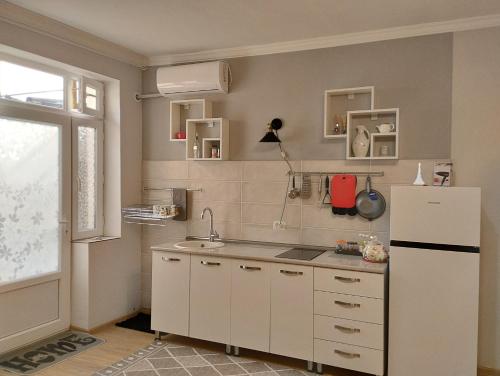 Kacharava apartments في تبليسي: مطبخ فيه دواليب بيضاء وثلاجة بيضاء