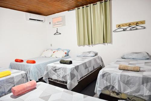 um quarto com três camas e uma janela em Hostel mineiros em Aracaju