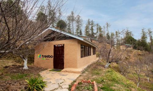 un pequeño edificio con una puerta en un bosque en Treebo Trend Daak Bangla Retreat With Mountain View, en Shimla