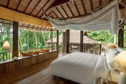 a bedroom with a bed and a balcony with trees at Six Senses Yao Noi in Ko Yao Noi