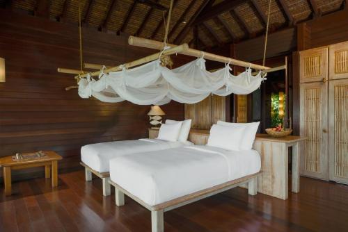 two beds in a room with wooden walls at Six Senses Yao Noi in Ko Yao Noi