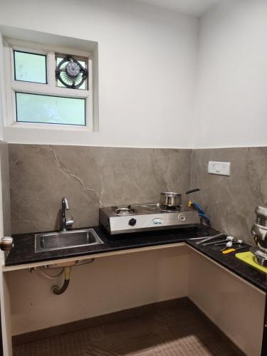 a kitchen with a sink and a stove and a window at Flora Embassy in Chennai